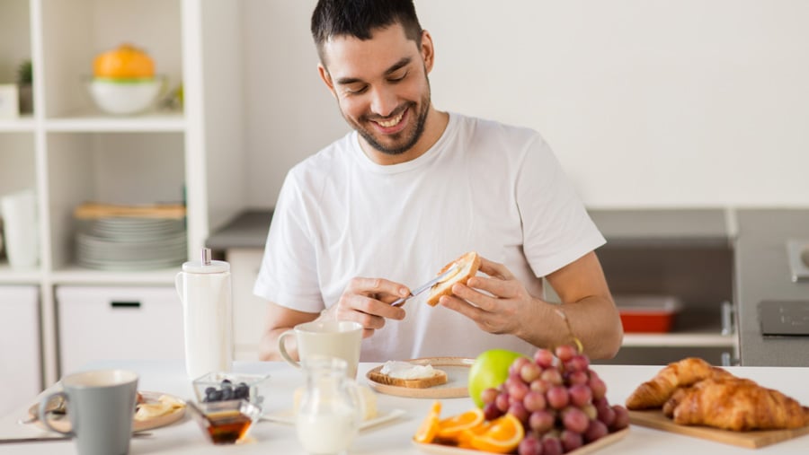 A man smiling as he makes breakfast