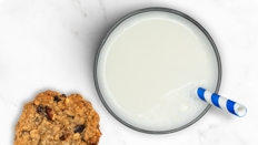 Vaso de leche LACTAID® con proteínas y galleta sobre encimera de mármol