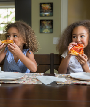 Dos niñas comiendo pizza alegremente