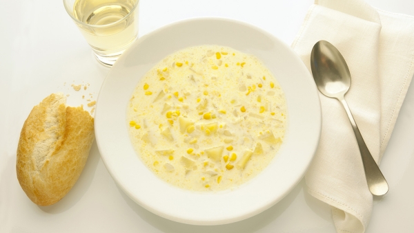 Sopa de maíz en un recipiente con pan y vino