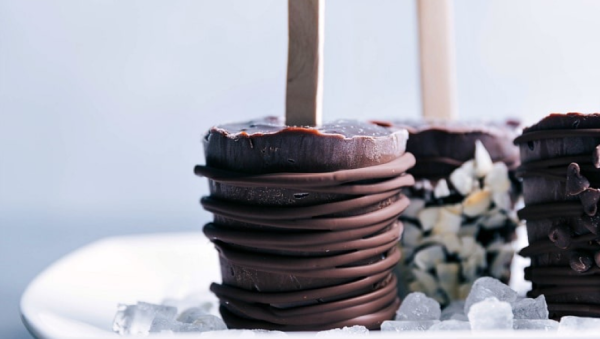 Paletas heladas de budín de chocolate amargo con diferentes decoraciones, como chocolate adicional y frutos secos